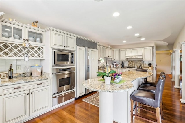 238 Berkeley Way, Monroeville, PA 15146 - kitchen featuring built in appliances, a warming drawer, decorative columns, dark wood-style floors, and a kitchen bar
