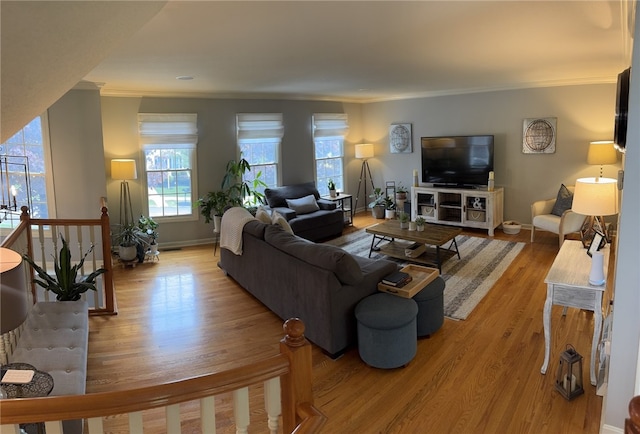 living area with crown molding, light wood-style floors, and baseboards