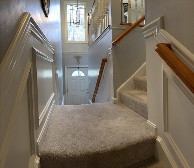 foyer entrance with a high ceiling, a chandelier, carpet flooring, and stairs