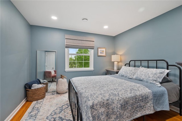 bedroom with wood finished floors, recessed lighting, and baseboards