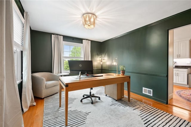 office space featuring light wood-type flooring and crown molding