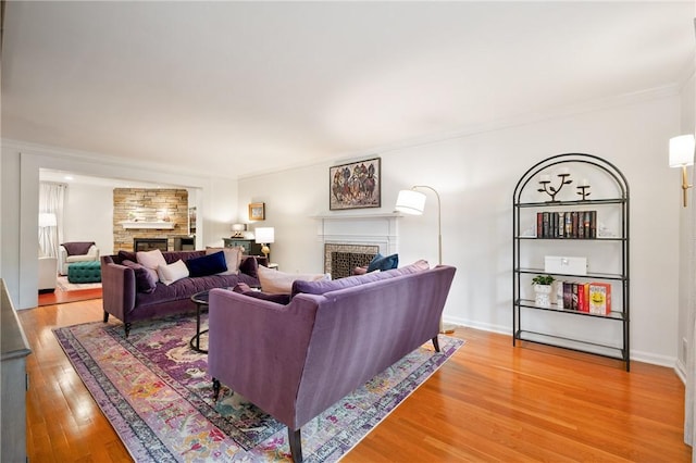 living room featuring a fireplace, light wood-type flooring, and ornamental molding