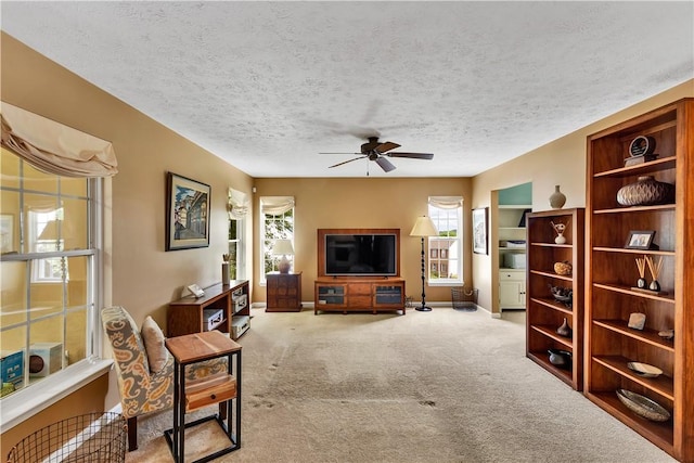 living room featuring a ceiling fan, carpet, a textured ceiling, and baseboards