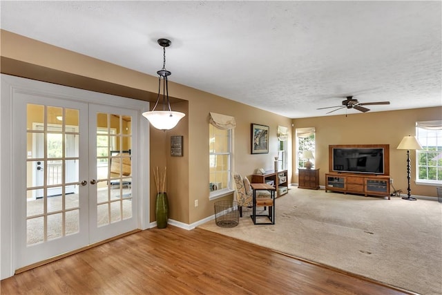 living area featuring french doors, wood finished floors, ceiling fan, baseboards, and a textured ceiling