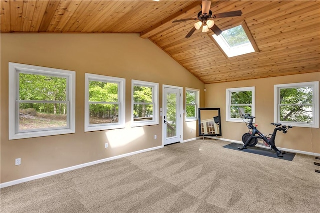 exercise room featuring ceiling fan, a skylight, vaulted ceiling, baseboards, and carpet