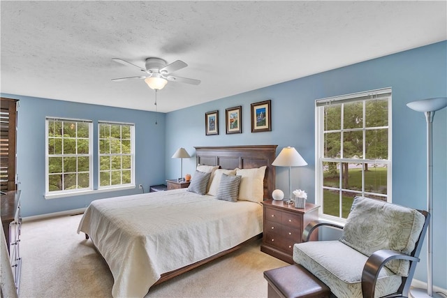 carpeted bedroom featuring ceiling fan, baseboards, and a textured ceiling