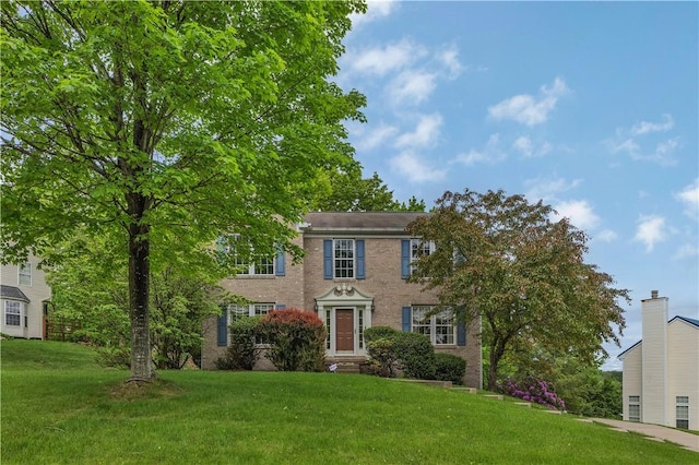 colonial-style house featuring a front yard