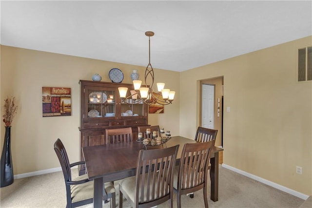 dining space with light colored carpet, a chandelier, and baseboards
