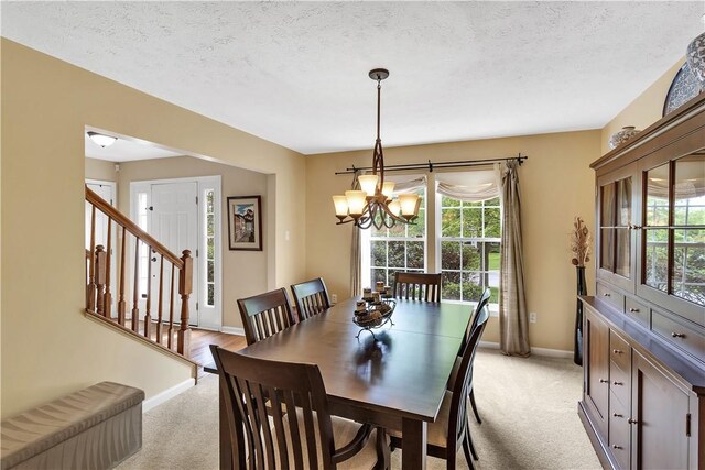 dining area featuring light colored carpet, healthy amount of natural light, a chandelier, baseboards, and a textured ceiling