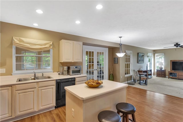 kitchen with dishwasher, a sink, open floor plan, light wood-style flooring, and a kitchen breakfast bar