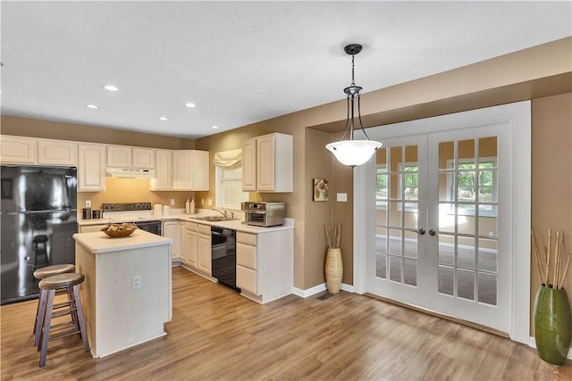 kitchen featuring black appliances, under cabinet range hood, french doors, a sink, and baseboards