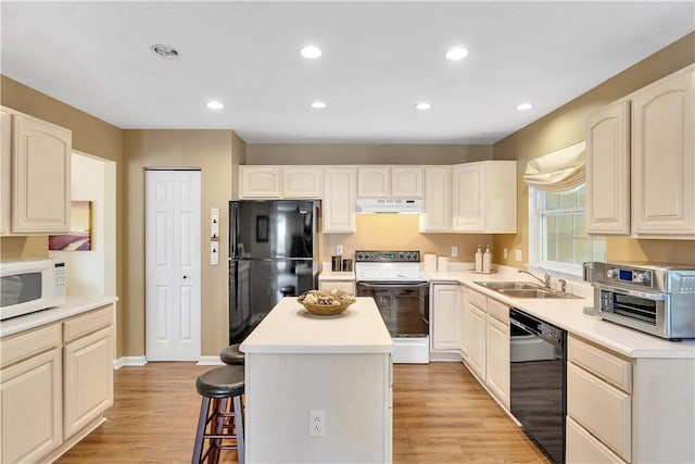 kitchen with black appliances, a sink, under cabinet range hood, a kitchen bar, and a center island