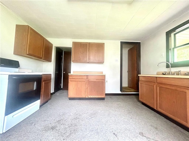 kitchen featuring electric range oven, light countertops, brown cabinets, and light colored carpet