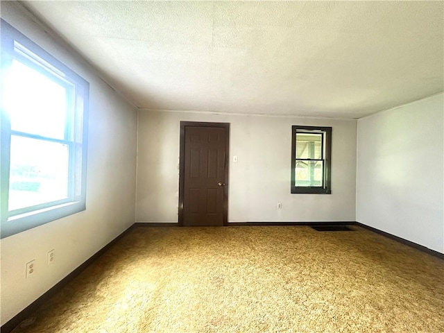 spare room with a textured ceiling and baseboards