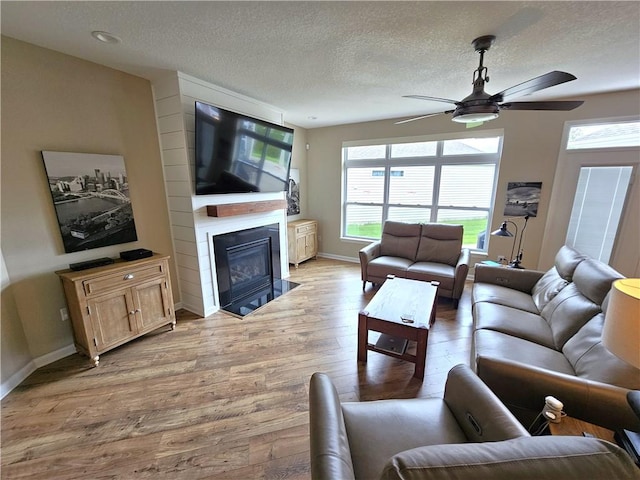 129 Bay Ct, Chartiers, PA 15301 - living room featuring a ceiling fan, light wood-style floors, a fireplace with flush hearth, a textured ceiling, and baseboards
