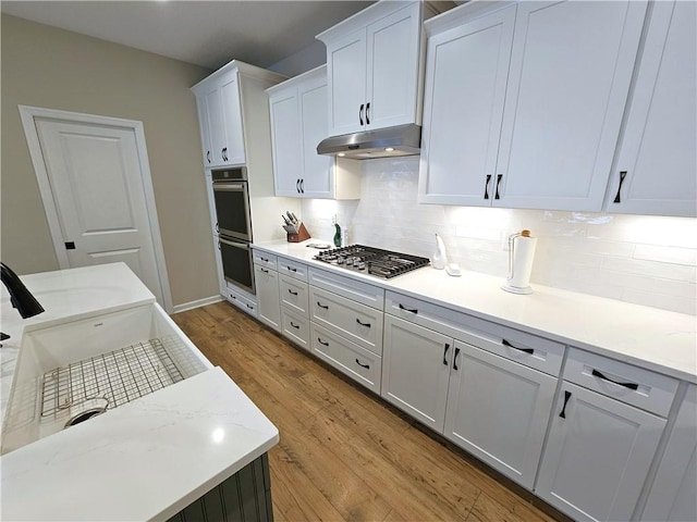 129 Bay Ct, Chartiers, PA 15301 - kitchen featuring appliances with stainless steel finishes, under cabinet range hood, backsplash, white cabinets, and light wood-style flooring