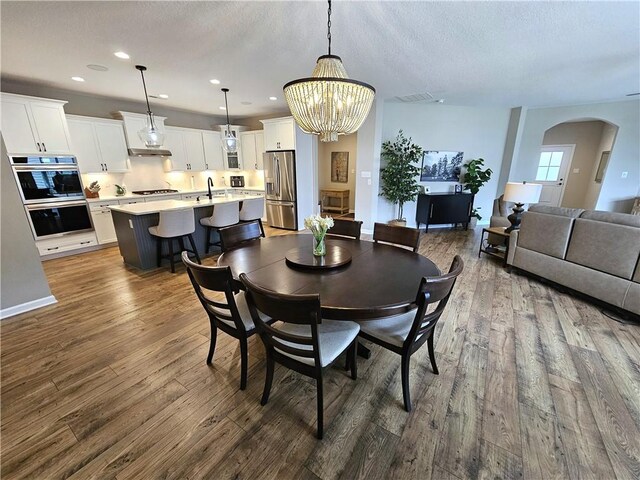129 Bay Ct, Chartiers, PA 15301 - dining area featuring arched walkways, dark wood-style flooring, recessed lighting, a chandelier, and a textured ceiling
