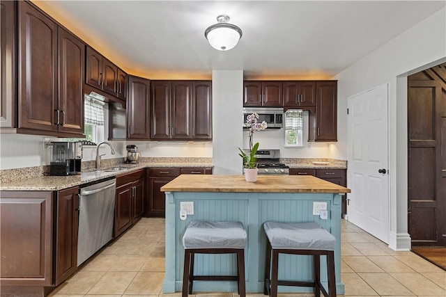106 Haldane St, Crafton, PA 15205 - kitchen featuring stainless steel appliances, light tile patterned floors, dark brown cabinets, and a kitchen breakfast bar