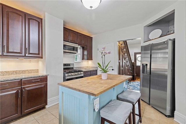 106 Haldane St, Crafton, PA 15205 - kitchen featuring stainless steel appliances, wooden counters, light tile patterned floors, a breakfast bar, and a center island
