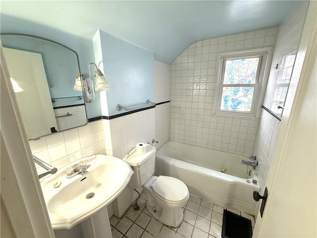 full bathroom featuring tile patterned floors, toilet, tile walls, a sink, and lofted ceiling