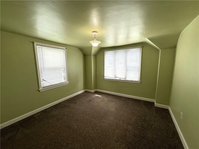 bonus room featuring lofted ceiling, dark carpet, and baseboards