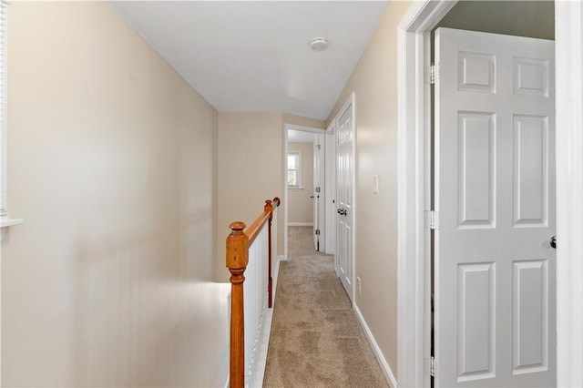 corridor with carpet floors, baseboards, and an upstairs landing