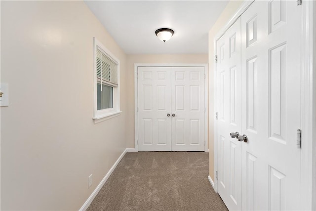 hallway with dark colored carpet and baseboards
