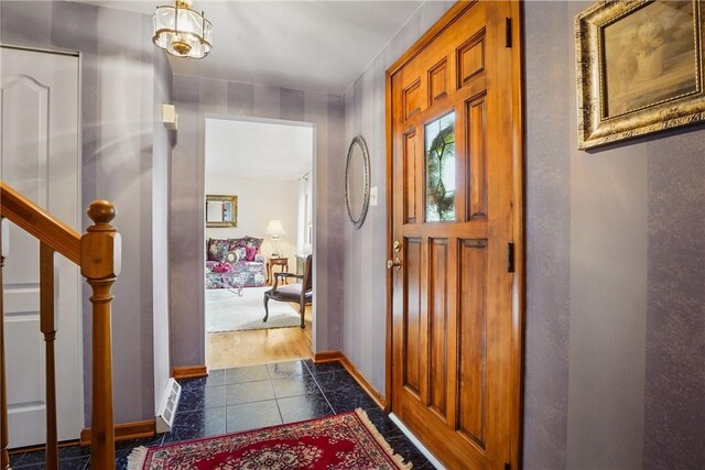 tiled foyer with baseboards and stairs