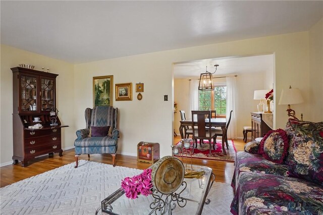 living area featuring wood finished floors, a chandelier, and baseboards
