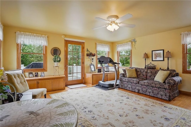 living area with ceiling fan, light wood-style floors, and baseboards