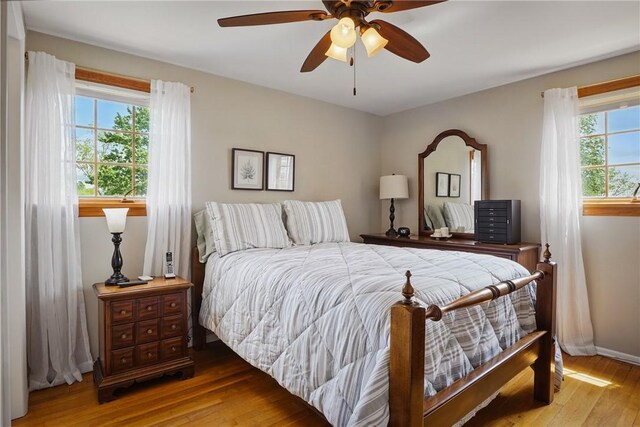 bedroom featuring hardwood / wood-style floors, a ceiling fan, and baseboards