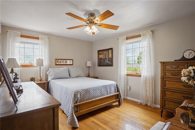 bedroom featuring light wood-type flooring, baseboards, and ceiling fan