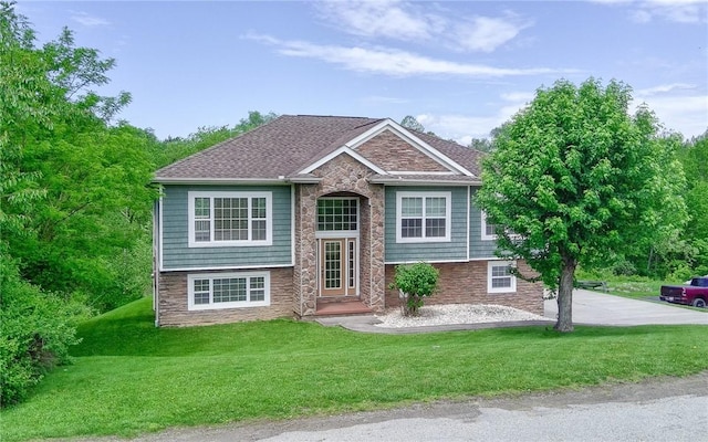 split foyer home featuring stone siding and a front yard