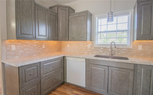 kitchen featuring dishwasher, a sink, tasteful backsplash, and wood finished floors