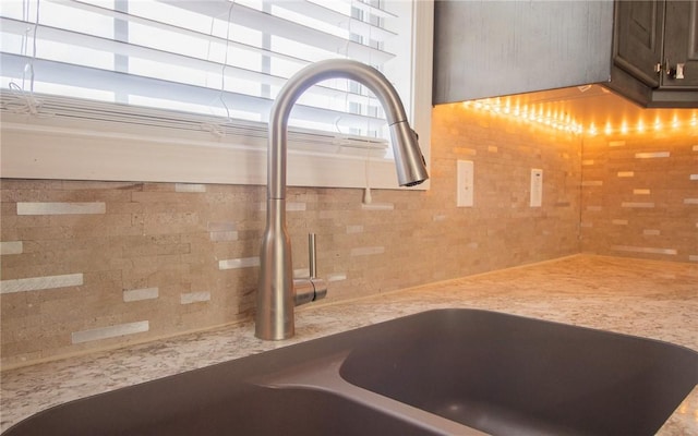 kitchen view of a sink, tasteful backsplash, light countertops, and dark brown cabinets
