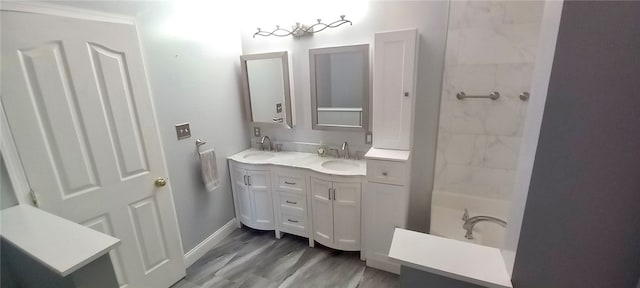 bathroom with double vanity, wood finished floors, and baseboards