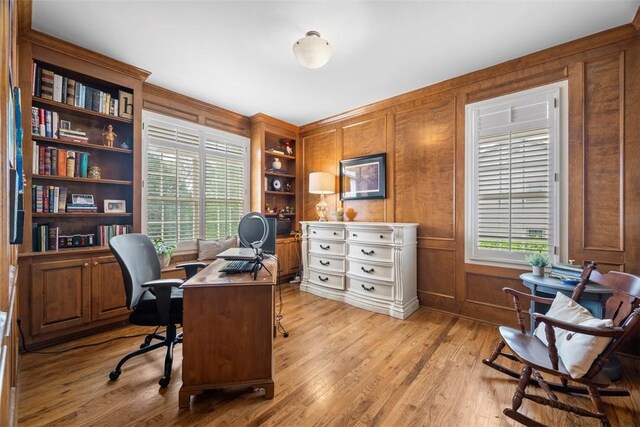 office space featuring light wood finished floors, built in features, and wooden walls