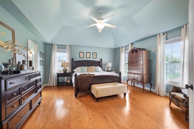 bedroom with lofted ceiling, light wood-type flooring, baseboards, and a ceiling fan