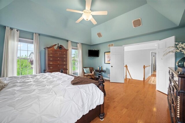 bedroom with light wood-type flooring, lofted ceiling, and a ceiling fan