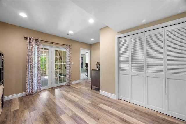 unfurnished living room with french doors, light wood-type flooring, baseboards, and recessed lighting