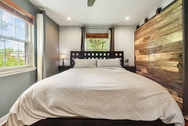 bedroom featuring multiple windows, recessed lighting, and wooden walls