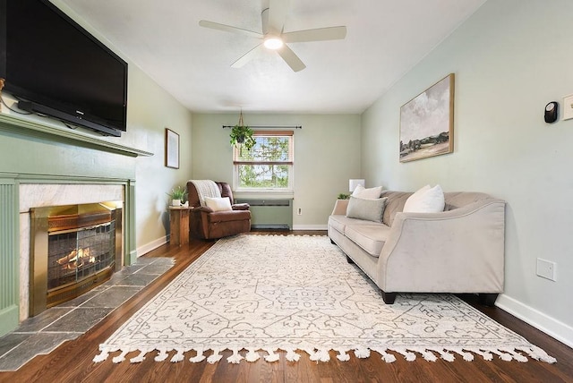 living room with a premium fireplace, ceiling fan, wood finished floors, and baseboards
