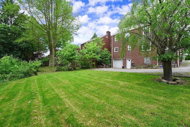 view of grassy yard featuring driveway and a garage