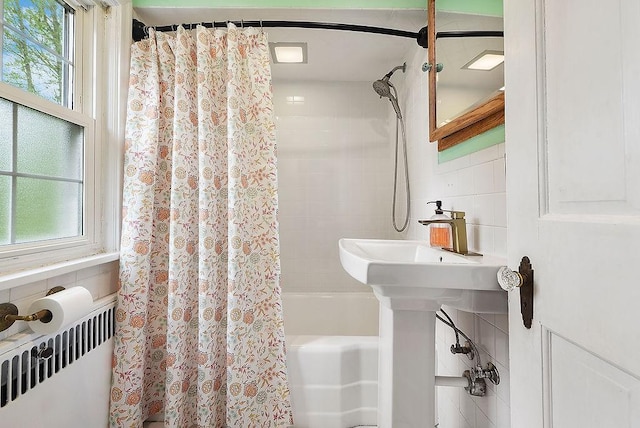 bathroom featuring plenty of natural light, shower / bath combination with curtain, radiator, and tile walls