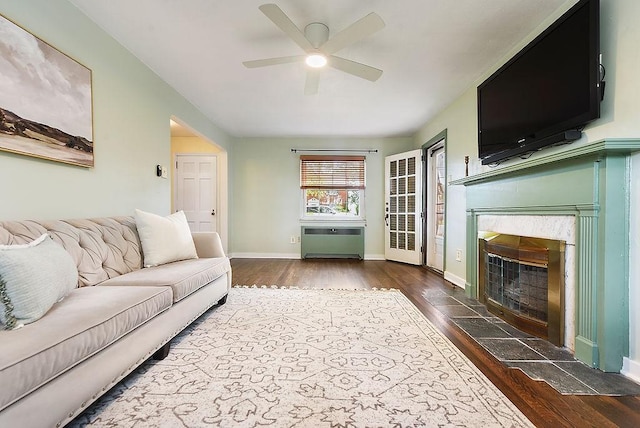 living area with hardwood / wood-style floors, a ceiling fan, a high end fireplace, radiator heating unit, and baseboards
