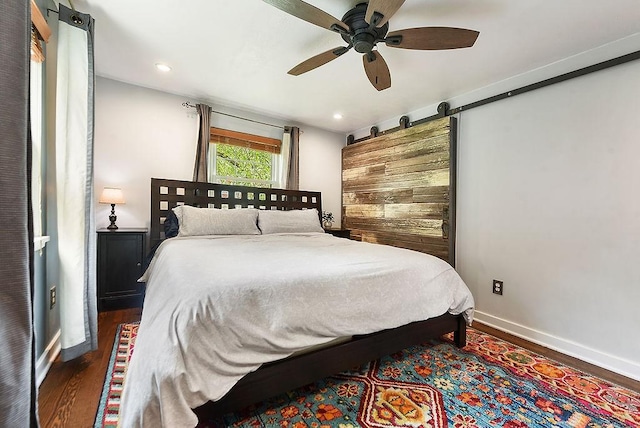 bedroom featuring wood finished floors, baseboards, recessed lighting, ceiling fan, and a barn door