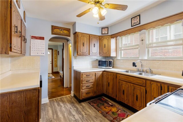 57 Laurel Ave, City Of Washington, PA 15301 - kitchen with a sink, stainless steel microwave, arched walkways, decorative backsplash, and brown cabinetry