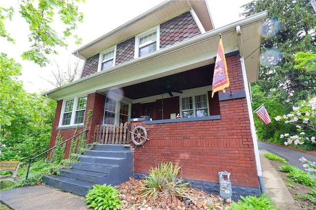 view of front of home featuring brick siding, a ceiling fan, and a porch