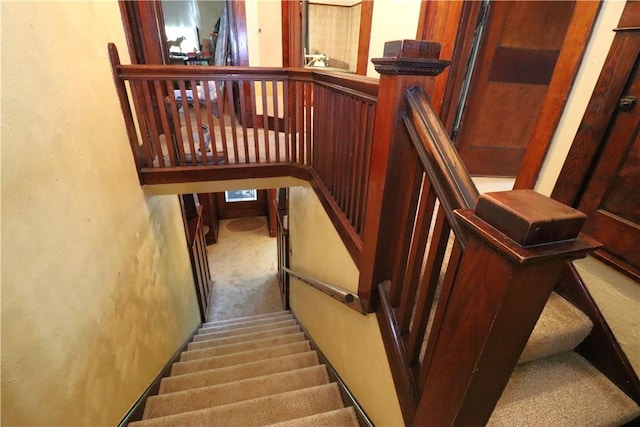 staircase featuring carpet floors and a textured wall