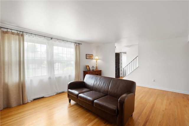 living area with light wood-style floors, stairs, and baseboards